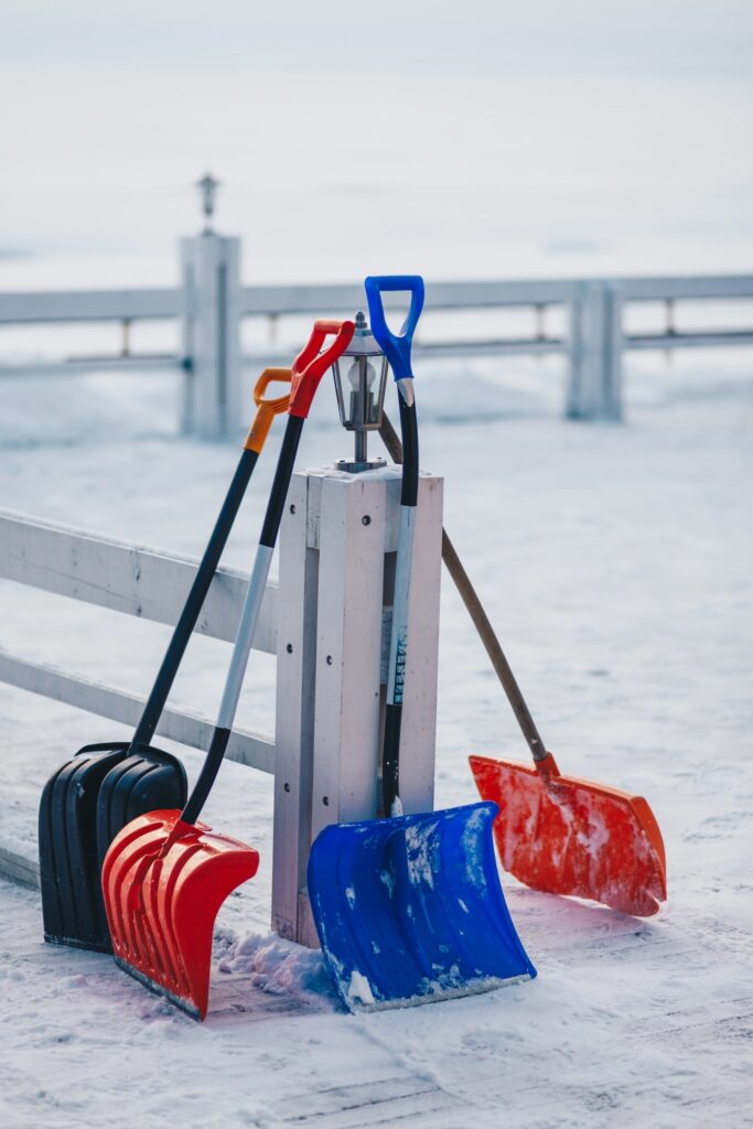 Vertical outdoor shot of plastic scoop for removing snow. Shovel in snow